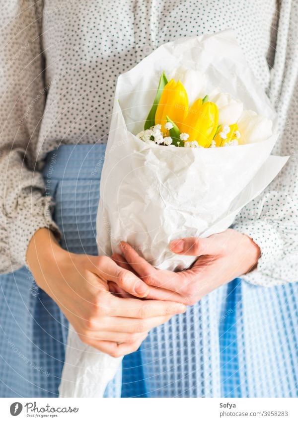 Frau hält Tulpenstrauß. Der Tag der Frau Blume Haufen Mutter geben Frühling Ostern Hände geblümt weiß gelb Dame März Geschenk Einladung Gruß Postkarte