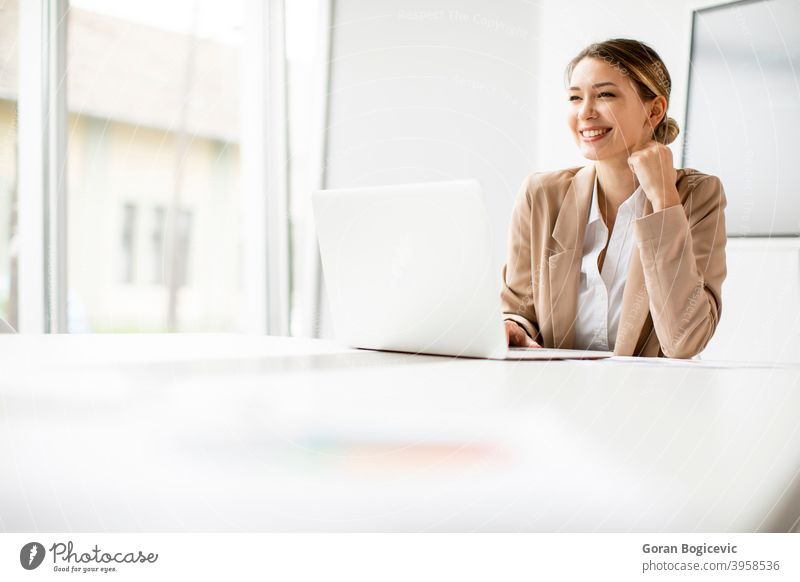 Junge Frau arbeitet am Laptop in hellem Büro mit großem Bildschirm hinter ihr Erwachsener attraktiv schön Business Kaukasier Mitteilung Computer selbstbewusst