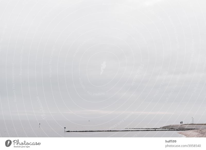 zwei Menschen stehen an einer Landzunge /Buhne  und schauen auf das Meer - Winter im Norden Nordseeküste pärchen seichtes Wasser Erholung Wattenmeer Seeufer