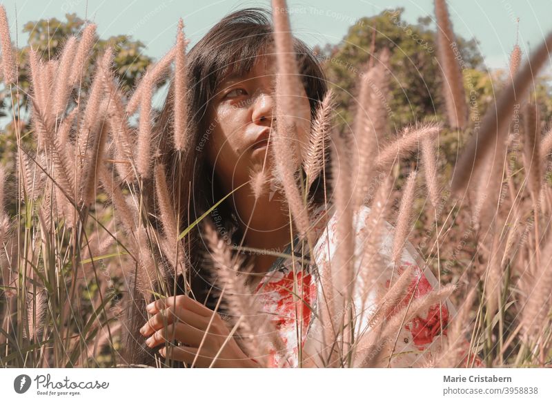 Schöne asiatische Mädchen unter der Wiese des Brunnens Gräser asiatische Frau konzeptionell natürlich Emotion Ruhe Windstille Glückseligkeit sonnig Sinnlichkeit