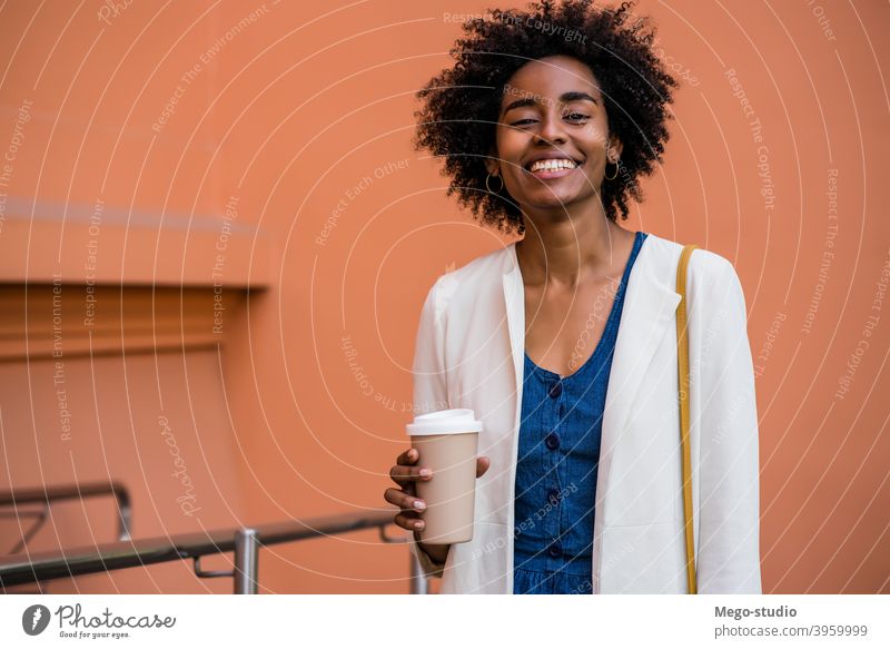 Afro-Geschäftsfrau hält eine Tasse Kaffee im Freien. Afro-Look Business Frau urban Lächeln Erwachsener Kaffee zum Mitnehmen Anzug Unternehmen Geschäftsleute