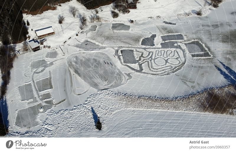 Luftaufnahme mit einer Drohne von einem zugefrorenen See im Winter mit Schlittschuhläufern luftaufnahme drohnenfoto see eis eislaufen wintersport schnee