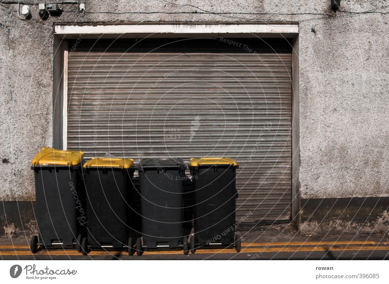 NCH | muelltonnen Fassade dreckig Müll Müllbehälter Müllabfuhr gelb Garage Garagentor schäbig geschlossen Reihe Recycling Farbfoto Gedeckte Farben Außenaufnahme