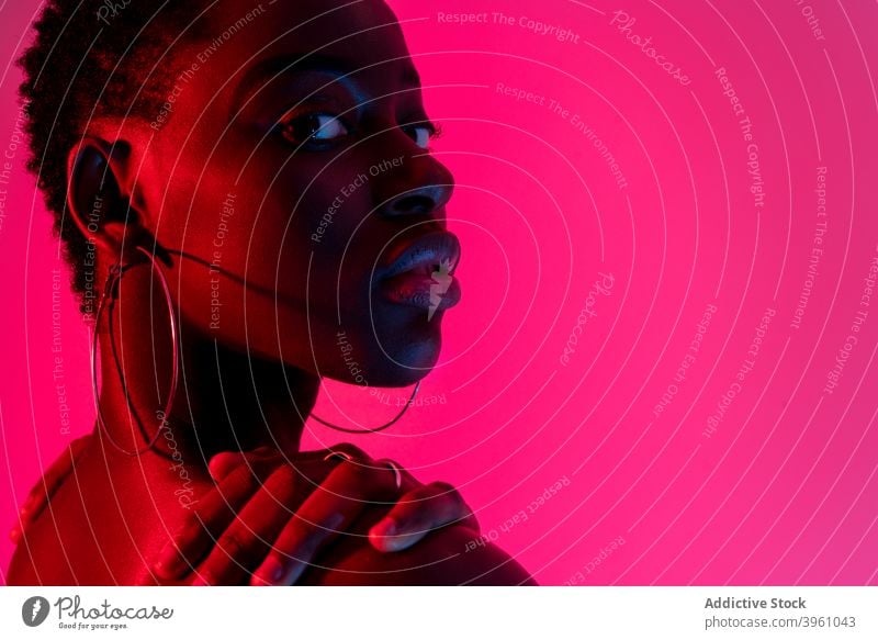 Verführerische junge schwarze Dame Blick auf die Kamera in neon rosa Studio Frau selbstsicher Verlockung Mode Model Porträt neonfarbig feminin sinnlich