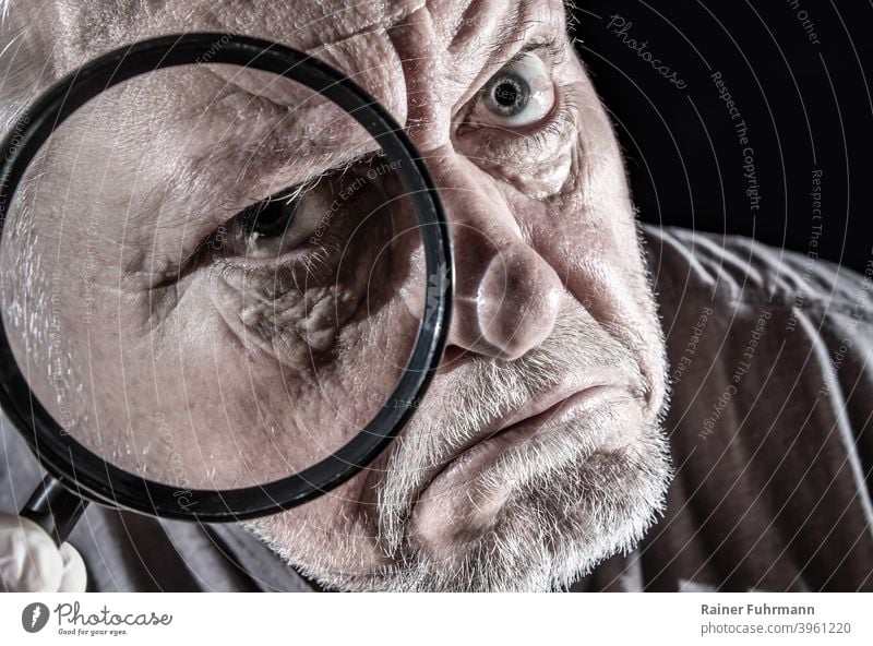ein Mann schaut skeptisch durch eine große Lupe Porträt sehen schauen beobachten Gesicht Blick Auge Mensch Farbfoto Blick in die Kamera Erwachsene Kopf Neugier