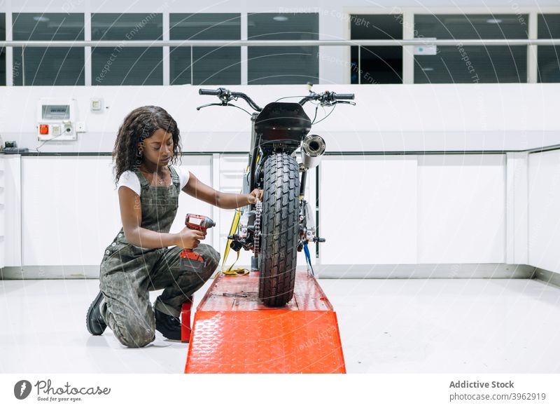 Schwarze Frau repariert Motorrad in Garage Mechaniker fixieren Werkstatt Reparatur Schraubenschlüssel Dienst ethnisch schwarz Afroamerikaner Arbeit Techniker