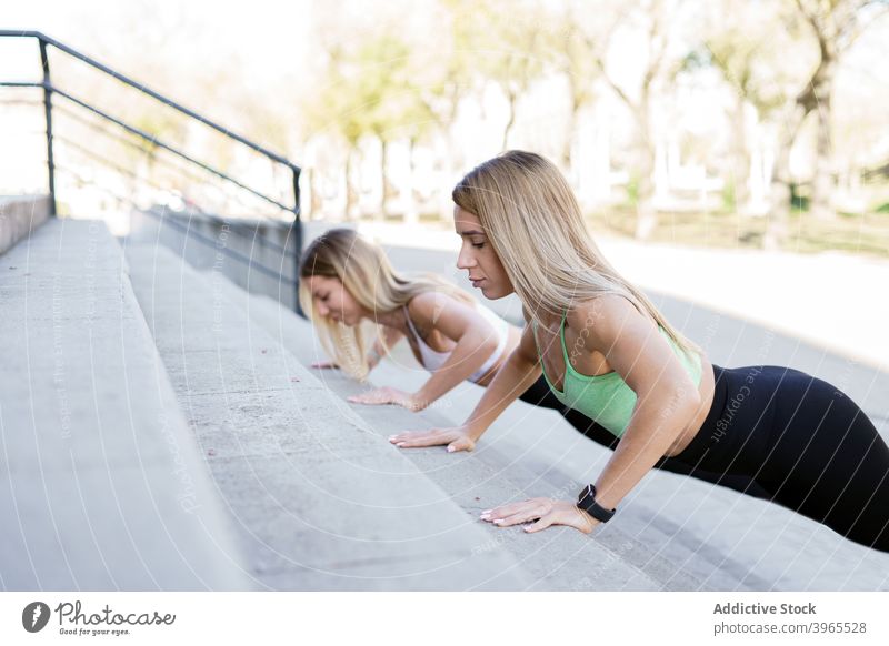 Schlanke Athleten machen Liegestütze in der Stadt Sportlerinnen hochschieben Training Großstadt schlank Treppe Übung schlanke Frau Beton passen physisch