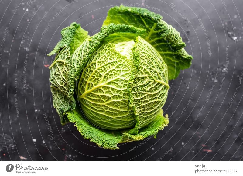 Ein roher Wirsing auf einem schwarzen Hintergrund. Draufsicht Kohl grün Gemüse Lebensmittel Ernährung Vegetarische Ernährung Gesundheit Bioprodukte Farbfoto