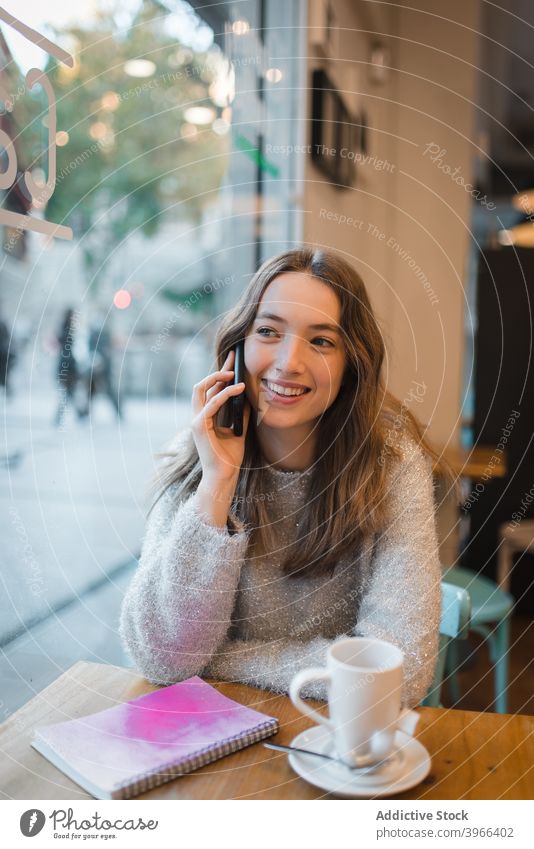 Frau spricht auf Smartphone im Café reden Lächeln diskutieren sprechen Kantine sich[Akk] entspannen Kälte Gerät Tisch charmant heiter Inhalt Anschluss modern