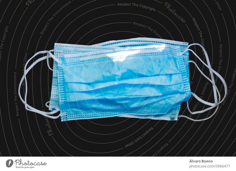Entsorgte Gesichtsschutzmaske aus Kunststoff, auf dunklem Hintergrund. schützend Mundschutz dreckig verwendet knittern vereinzelt Einwegartikel Farbe blau