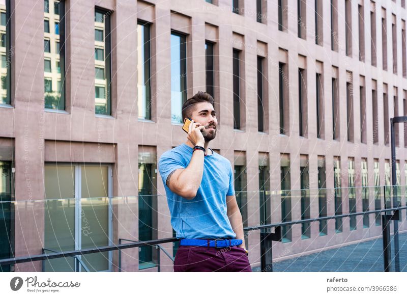 Porträt eines fröhlichen modernen Geschäftsmannes, der am Telefon spricht und lächelt, während er im Freien steht Gebäude Mann sprechend Mobile Großstadt