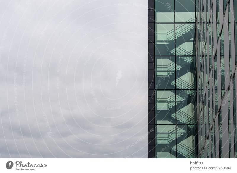 Transparentes Treppenhaus mit wolkigem Himmel - es ist kalt draussen. grün Treppengeländer düster dunkel diffus transparenz Hochhaus Architektur