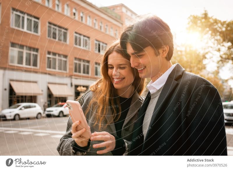Verliebtes junges Paar steht mit Smartphone auf der Straße Liebe Zusammensein Glück Partnerschaft Umarmen Freundin heiter Lifestyle romantisch Zuneigung