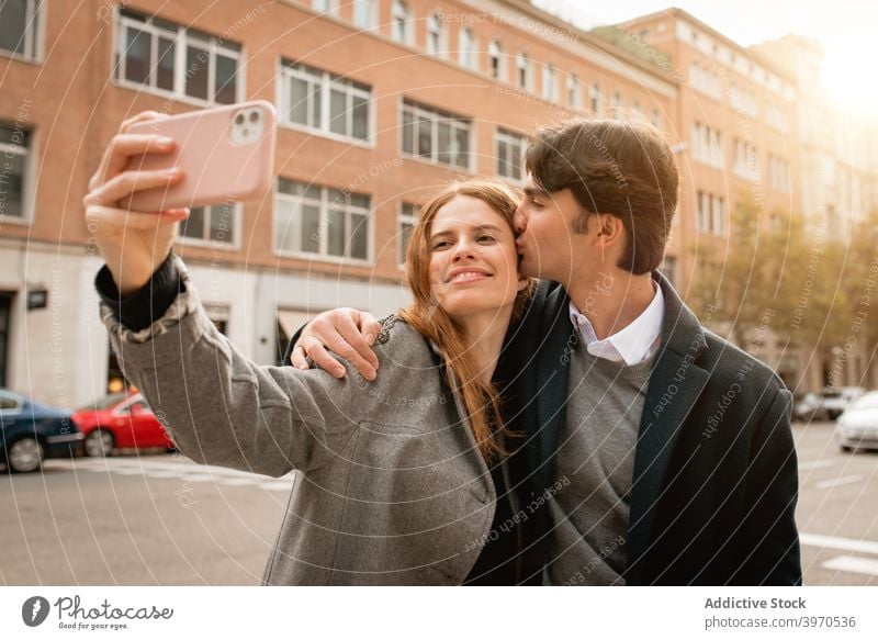 Verliebtes junges Paar nimmt Selfie auf der Straße Liebe Kuss Zusammensein Glück Smartphone Partnerschaft Umarmen Freundin heiter Lifestyle romantisch Zuneigung