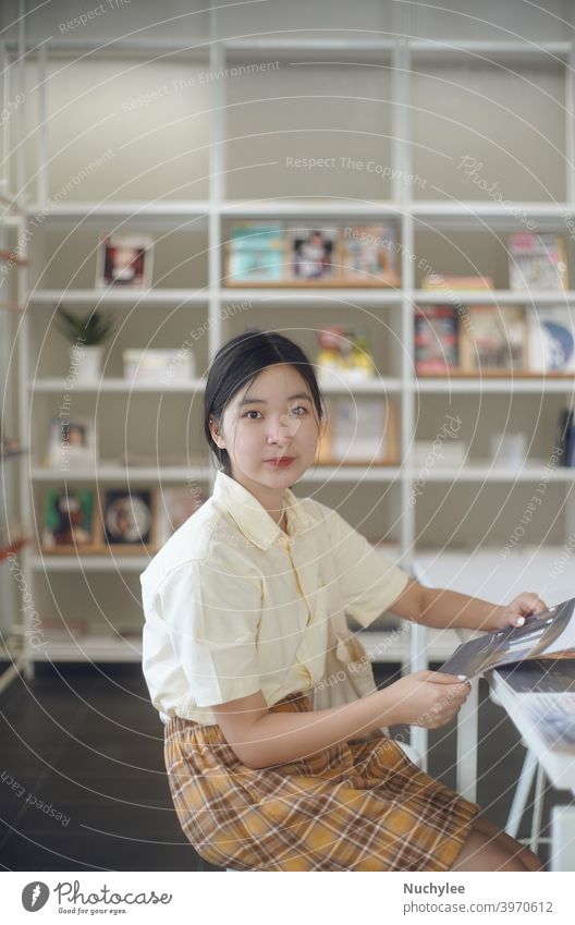 Junge asiatische Millennial Teenager-Mädchen in der modernen Bibliothek in der Schule oder Campus, Bildung und Lernen Konzept Hintergrund schön Buch brünett