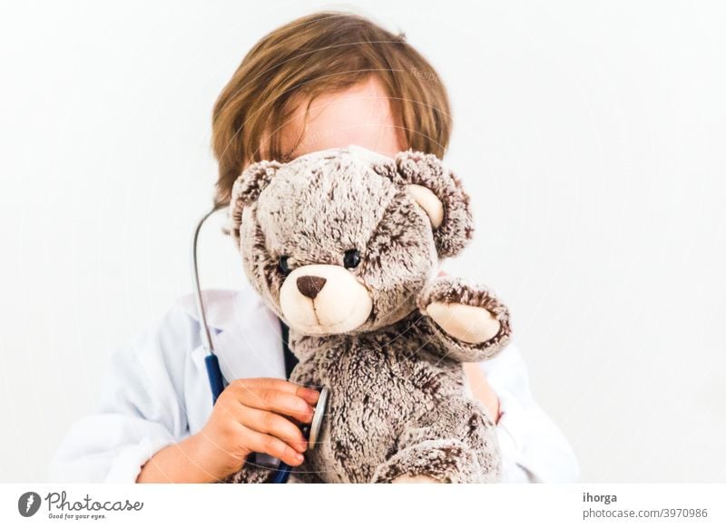 Junge als Arzt gekleidet auskultieren Teddybär auf weißem Hintergrund bezaubernd Auskultieren Baby Bär Pflege heiter Kind Kindheit Klinik Kleidung Konzepte