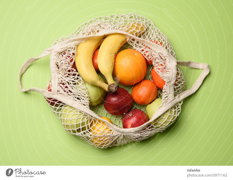 reifen frischen Früchten in einem Textil-String Tasche auf einem grünen Hintergrund, Ansicht von oben Top ineinander greifen Gesundheit natürlich