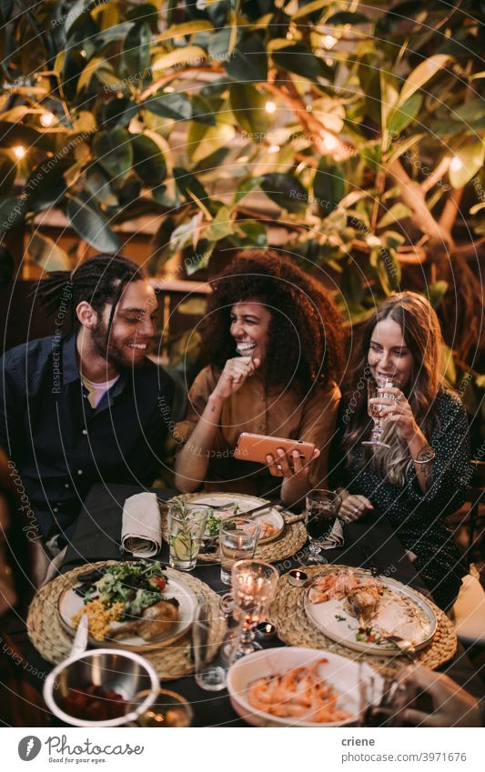 Diverse Gruppe von Freunden lachen und Spaß haben mit Telefon im Garten Abendessen Partei offen Fröhlichkeit Smartphone Lächeln junger Erwachsener