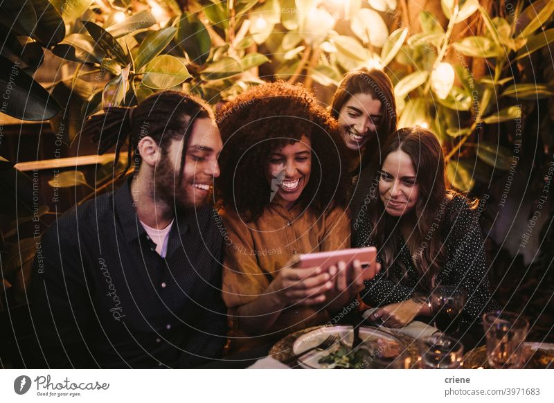Gruppe von jungen erwachsenen Freunden, die auf das Telefon schauen und Spaß auf einer Party haben offen Fröhlichkeit Smartphone Lächeln junger Erwachsener