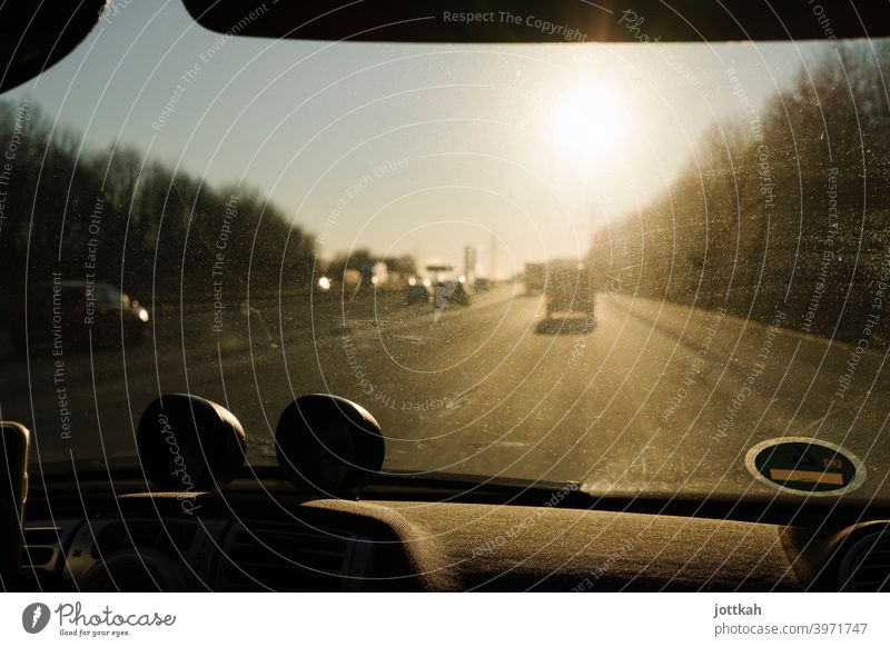 Durch die dreckige Frontscheibe eines Autos sieht man die Autobahn und die blendende Sonne fahren unterwegs mobil Mobilität Roadtrip PKW Straße Verkehr