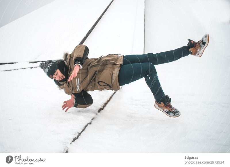 Mann rutscht auf Eis aus und fällt hin Ausrutschen und Sturz Ausrutschen auf Eis Rutschgefahr rutschig ausrutschen ausgerutscht fallen fallend Winter Schnee