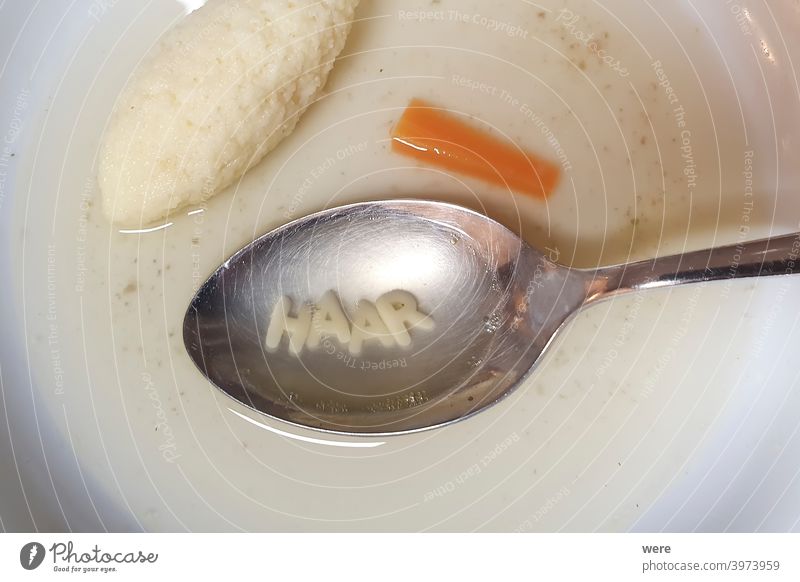 Löffel mit Buchstaben Suppennudeln in einem weißen Suppenteller neben Grießnockerl und Karotte deutscher Text Haar Deutscher Text Brühe Möhre klare Suppe