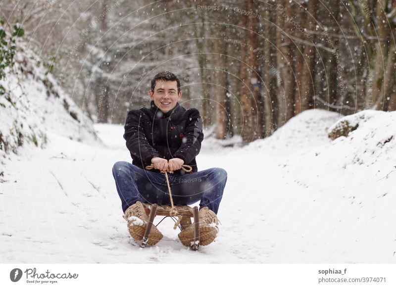 Mann fährt auf einem Schlitten, hat Spaß und lacht - Winterzeit & Schlittenspaß Rodel Schnee Reiten Lachen Fröhlichkeit Erwachsener Kindheit Rodeln Glück Freude