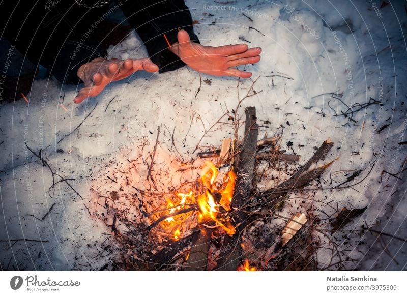 Gefrorene Männerhände wärmen sich in der Winternacht am Lagerfeuer. Hände Brennholz Erwärmung weiß Schnee Nacht Hintergrund Brand Freudenfeuer hell Brandwunde