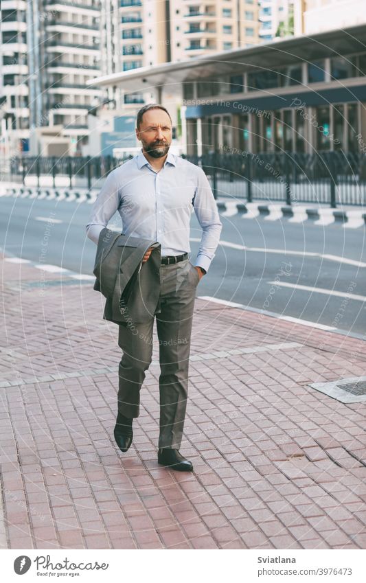 Porträt eines jungen Millennials, der mit einem Telefon in der Hand durch die Stadt läuft Büro Mann Geschäftsmann Smartphone modern gelungen Großstadt Anzug