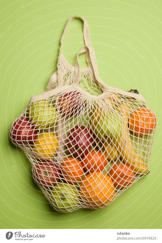 reifen frischen Früchten in einem Textil String Tasche auf einem grünen Hintergrund orange Apfel Banane Konzept Baumwolle Öko ökologisch Ökologie Lebensmittel