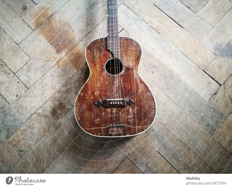 Alte braune defekte Gitarre mit gerissener Saite auf dem schönen alten Holzboden eines Bauernhaus in Oberbayern Musikinstrument Hippie kaputt Musiker Patina