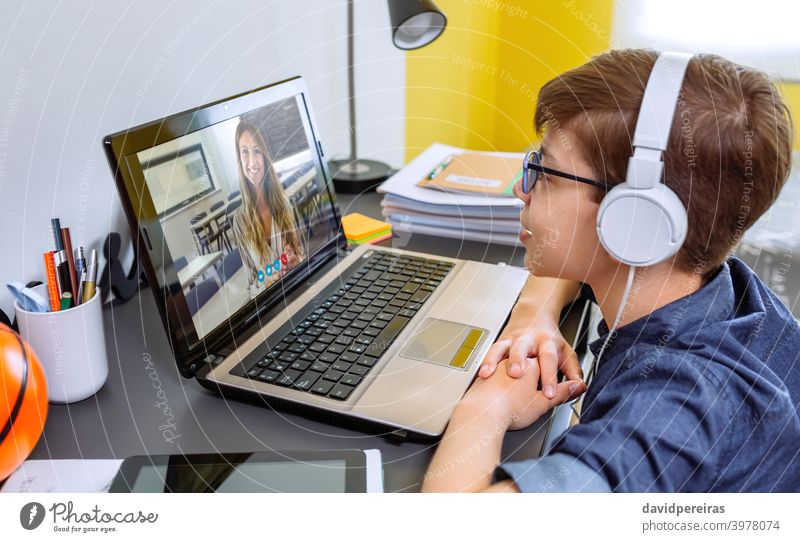 Junge mit Kopfhörer erhalten Klasse zu Hause mit Laptop aus seinem Schlafzimmer Heimunterricht Schule zu Hause Lehrer Videoanruf Jugendzimmer sprechend