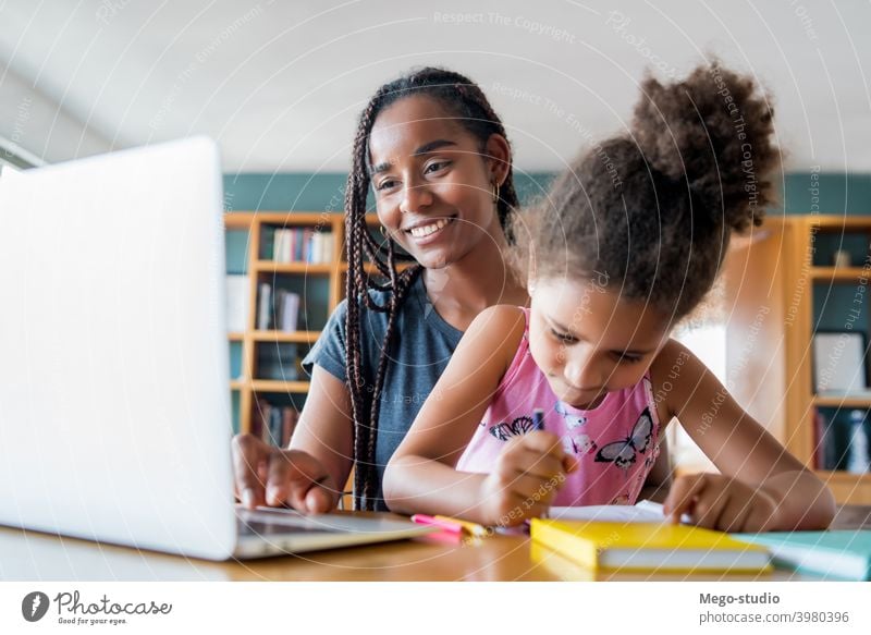 Eine Mutter hilft ihrer Tochter bei der Hausaufgabenbetreuung. Laptop Schule online Schüler Lernen Lifestyle Quarantäne Familie Kinder Menschen absperren