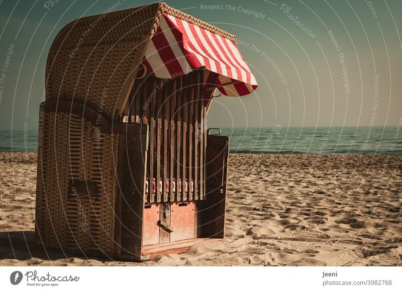 Ganz allein und verschlossen steht er da am Strand im Sand - der Strandkorb  mit einem rot-weißen Sonnenschutz - ein lizenzfreies Stock Foto von  Photocase