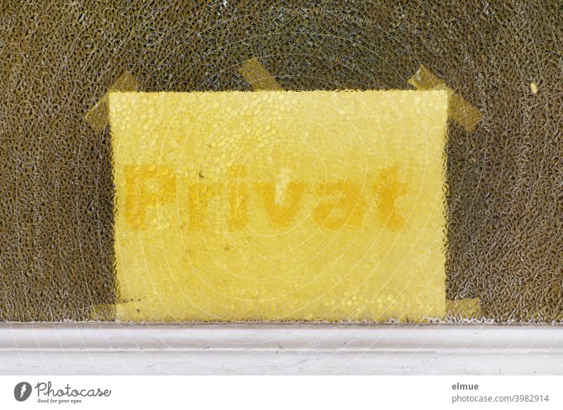 Hinter der strukturierten Glasscheibe einer Tür wurde mittels mehrerer Klebestreifen ein hellgelber Zettel mit gelber Aufschrift "Privat" angebracht / Privatsphäre