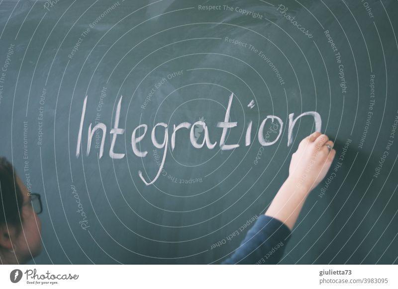 Junge Lehrerin schreibt mit Kreide das Wort Integration an die Tafel Intergration 18-25 Jahre Unterricht Tag Zentralperspektive Frau Schulunterricht Farbfoto