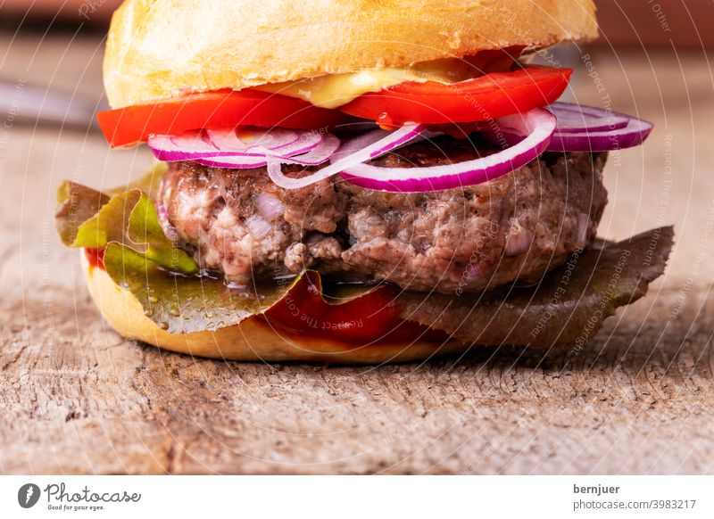 Nahaufnahme eines Hamburgers auf Holz Cheeseburger Hackfleisch Fleisch hausgemacht Zutat bbq schnell Burger Brötchen Zwiebel rot Zwiebelring gegrillt Salat