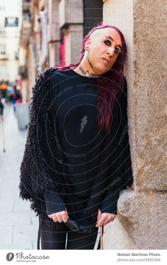 Porträt eines exzentrischen Rockers in schwarzer Kleidung. Er hat Tattoos und lange lila Haare. androgyn männlich schön jung Mann feminin Typ Nahaufnahme schwul