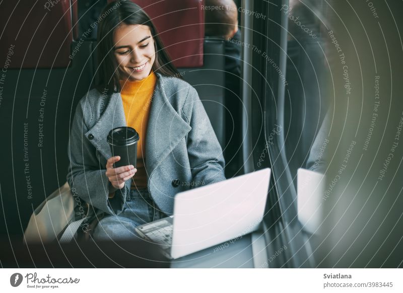 Freiberuflerin trinkt Kaffee und sitzt im Zug mit einem Arbeitslaptop. Moderne Technologien und Netzwerke Mädchen Laptop Technik & Technologie reisen Business