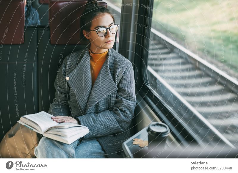 Junges schönes Mädchen in einem Zug, das ein Buch liest, während es in einem Zug reist Passagier Glück Reise Kaffee Tourist Ruhe lesen im Inneren Verkehr jung