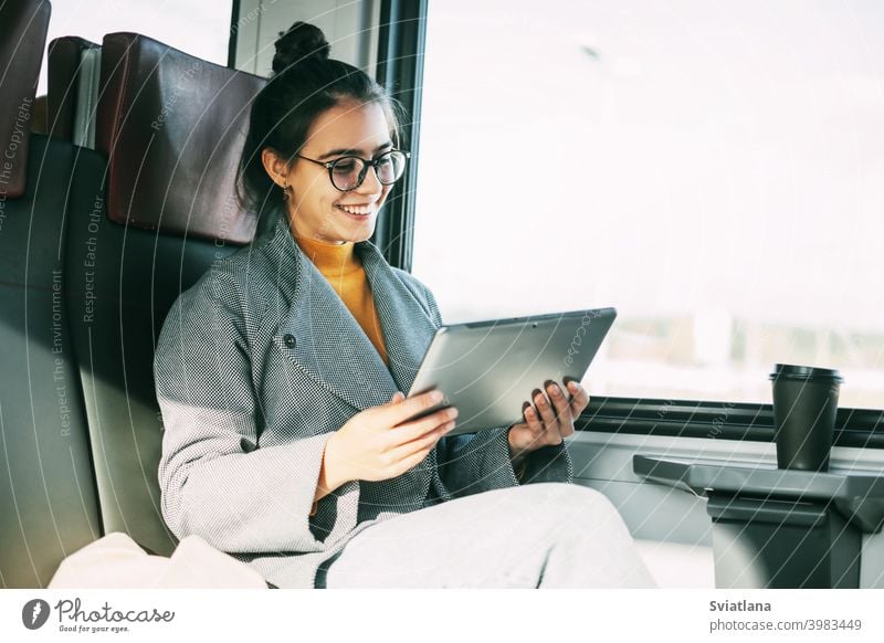 Junges Mädchen im Zug kommuniziert auf dem Tablet mit Freunden und Verwandten während der Fahrt im Zug Tablette Frau Passagier Glück reisend lesen eBook
