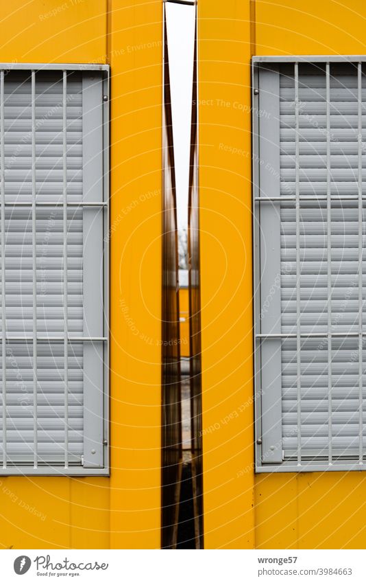 Blick durch den freien Spalt zwischen 2 gelben Baucontainern mit verschlossenen und vergitterten Fenstern Container Gelbe Container Freiraum Abstand Durchblick