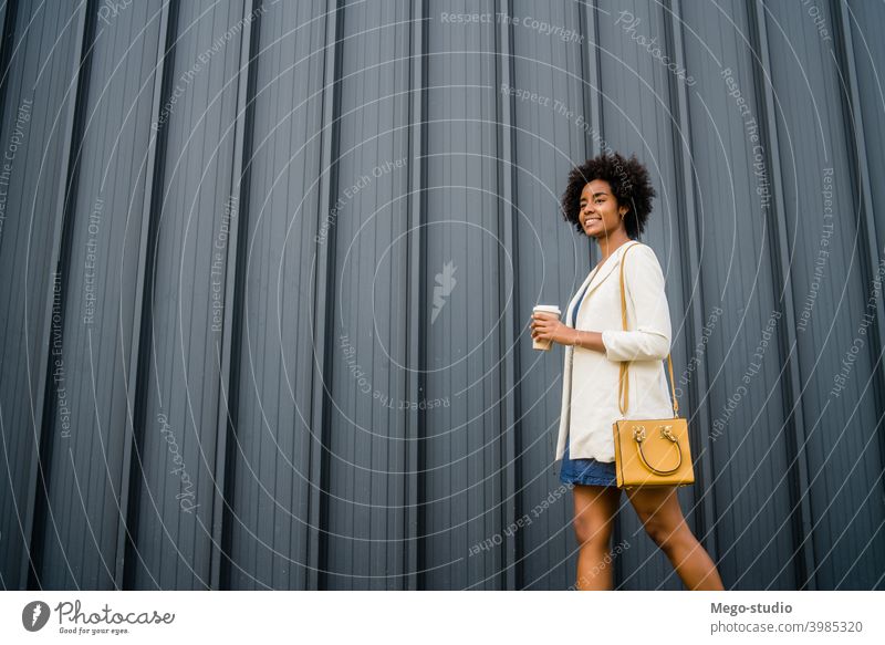 Porträt einer afroamerikanischen Geschäftsfrau beim Gehen im Freien. Afro-Look Business Frau urban Lächeln Erwachsener Kaffee Kaffee zum Mitnehmen Anzug