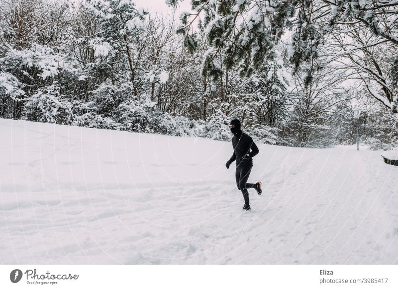 Ein Mann joggt im Winter durch den Schnee joggen laufen Sport Fitness Bewegung sportlich Park Natur Schneelandschaft Läufer Training Joggen Jogger