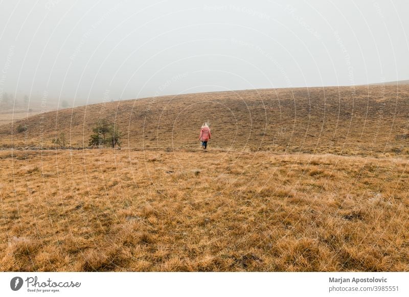 Junge Frau erkundet die Natur an einem nebligen Wintermorgen Abenteuer Herbst Cloud kalt Landschaft Fundstück Erkundung erkunden Entdecker Feld Nebel Freiheit
