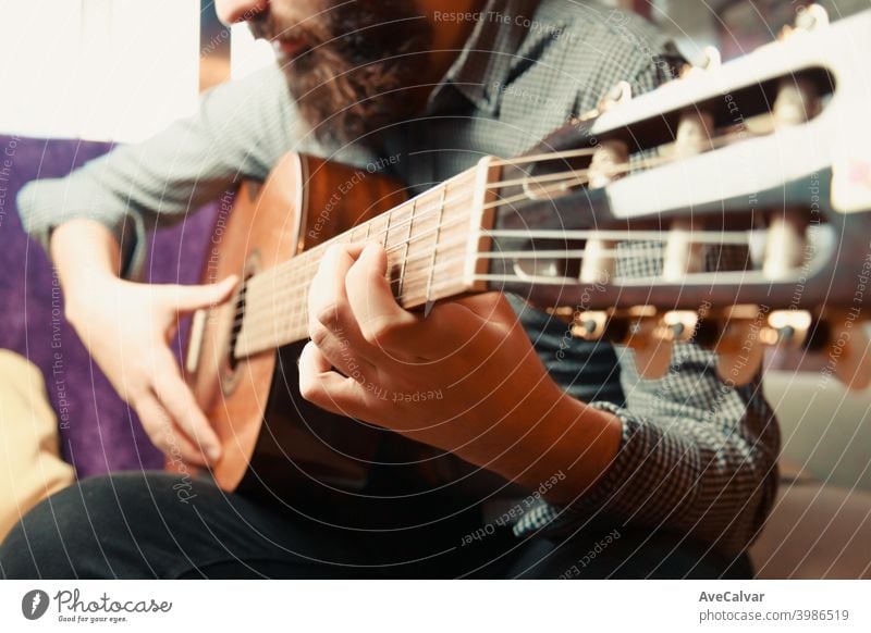 Eine Nahaufnahme der Hände eines bärtigen Mannes, der an einem hellen Tag spanische Gitarre spielt akustische Gitarre Kopierbereich Ausdrücken flippig Harmonie