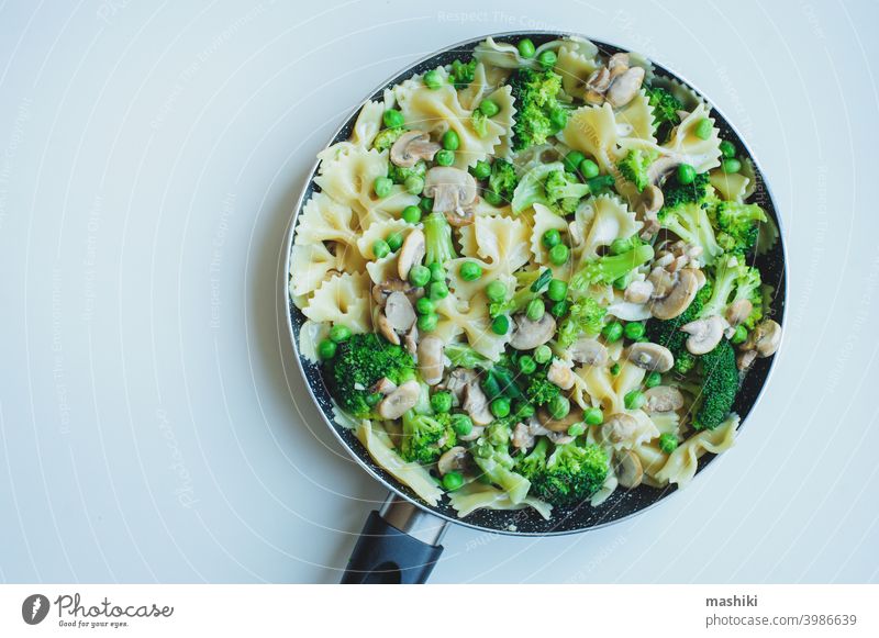 Pfanne mit gekochter schmackhafter italienischer vegetarischer Pasta mit Brokkoli, grünen Bohnen, Champignons in Sahnesoße. Schmackhaftes Mittag- oder Abendessen