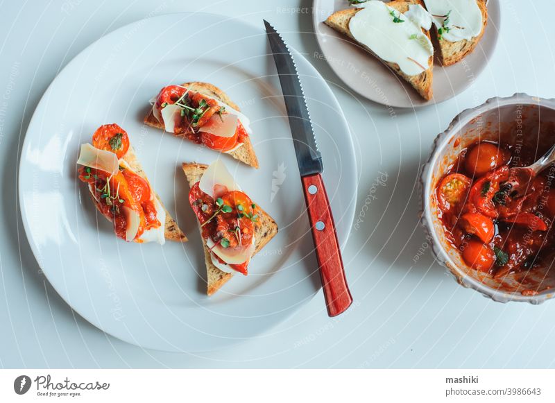 Köstliche italienische Vorspeise - Crostini-Toast mit gebackenen Kirschtomaten, Bauernkäse und Kräutern der Provence Belegtes Brot Tomate Lebensmittel