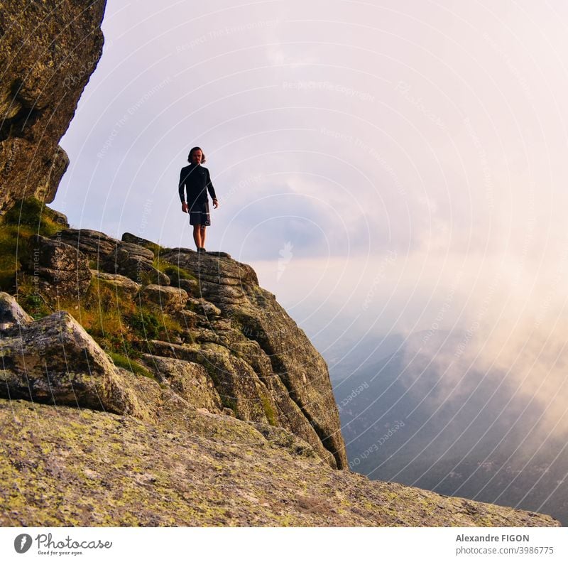 Ein Mann, der in den Bergen neben einem Canyon in Wolkenhöhe steht Berge u. Gebirge Gipfel Schlucht Wanderung Sonnenuntergang Steine farbenfroh Höhe