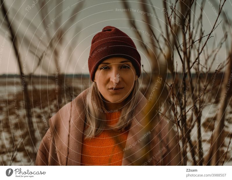 Portrait einer modisch gekleideten Frau in Winterlandschaft winterwonderland frau junge frau mantel spaziergang schnee sonne licht natur schal mütze lange haare